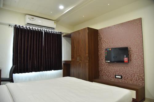 una camera con due letti e una TV a parete di Hotel Savera Inn a Morbi
