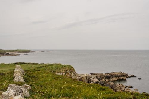 a view of a body of water with rocks and grass at Creevy Cottages in Rossnowlagh