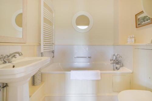 a white bathroom with a sink and a tub at Chestnut Lodge in East Dean