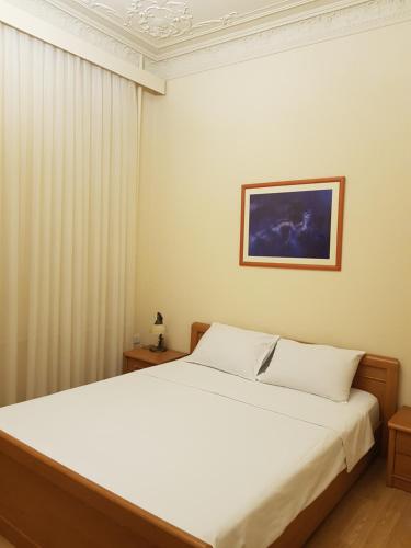 Central Baku Luxury Boulivard Apartment في باكو: غرفة نوم بسرير ابيض ولوحة على الحائط
