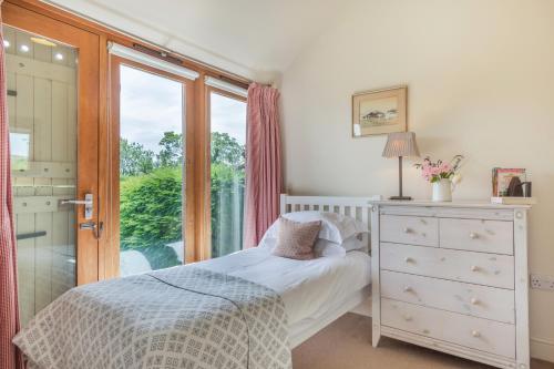 a bedroom with a bed and a window and a dresser at Chestnut Lodge in East Dean