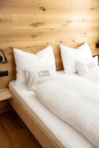 a bed with white sheets and pillows at Residence Kugler in San Candido