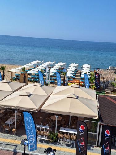 a row of umbrellas and tables and the ocean at STUDIO MARGARITA in Nea Plagia