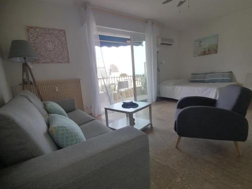 un salon avec un canapé, un lit et une table dans l'établissement Résidence l'Emilia, à Hyères