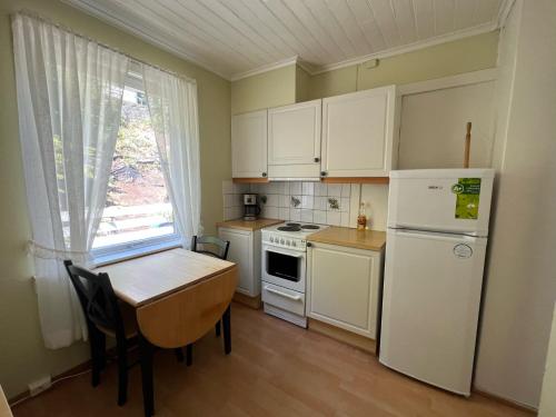 uma cozinha com armários brancos, uma mesa e um frigorífico em Odda City Apartments em Odda