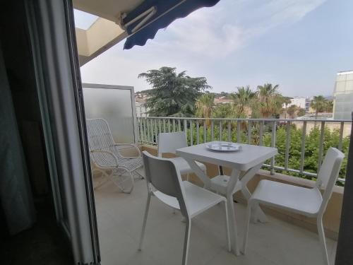 une table blanche et des chaises sur un balcon dans l'établissement Résidence l'Emilia, à Hyères