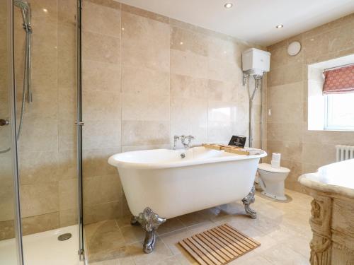 a bathroom with a tub and a shower and a toilet at The Farmhouse in North Walsham