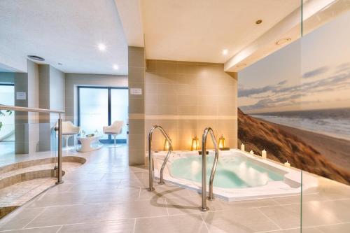 a bathroom with a bath tub with a painting on the wall at Atrium Oaza Sarbinowo in Sarbinowo