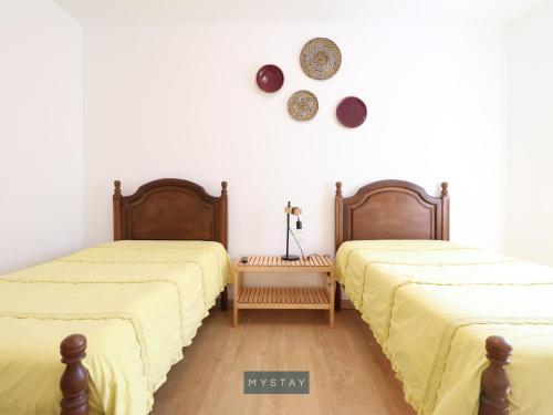 2 Betten in einem Zimmer mit weißen Wänden und Holzböden in der Unterkunft MyStay - Casa Esposende 