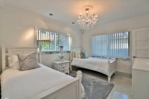 Habitación blanca con 2 camas y lámpara de araña. en Stunning 2bdr2bath Steps To The Beach, en Fort Lauderdale