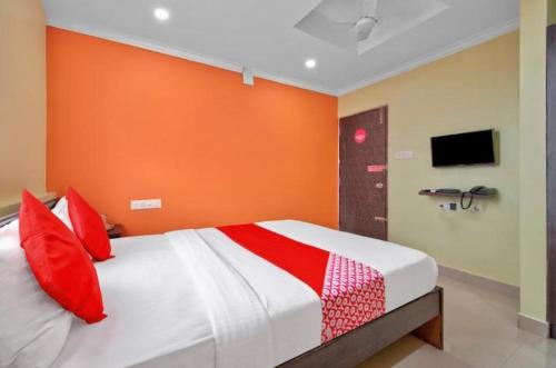 - une chambre avec un mur orange et un lit avec des oreillers rouges dans l'établissement MANAN PARADISE, à Bangalore