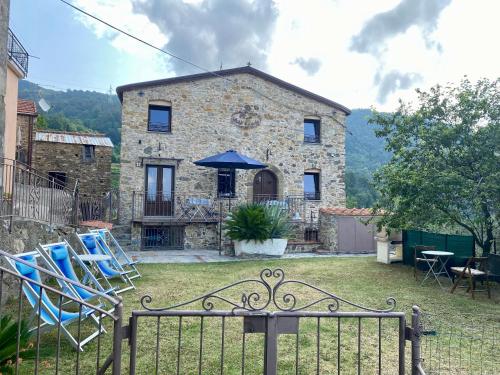 a stone house with chairs and an umbrella in a yard at Casa Dell'Angelo Cherubino Monolocale in Castelnuovo Magra