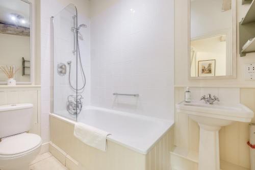 a white bathroom with a toilet and a sink at Giddy Cottage in East Dean
