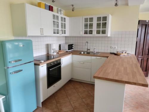 uma cozinha com armários brancos e um frigorífico azul em Chalet Forsthof Everstorf - kleine Wohnung em Grevesmühlen