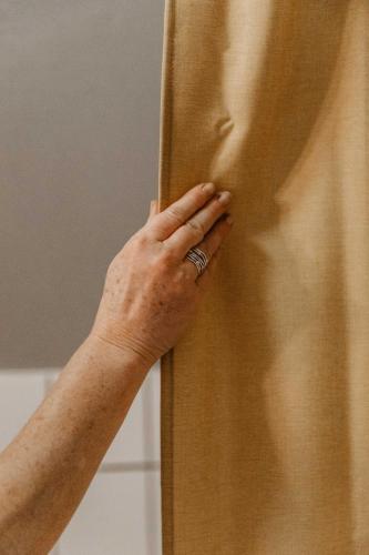 a person with a ring on their hand next to a curtain at Hotel Slottsvillan in Huskvarna