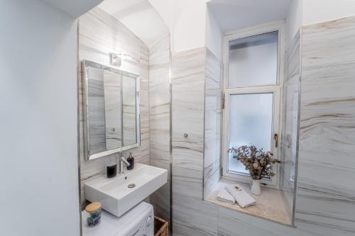 a white bathroom with a sink and a window at Kenti Residence in Ljubljana