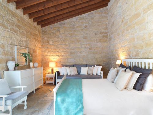 1 dormitorio con 1 cama grande y pared de piedra en Villa Avgoustis, en Pachna