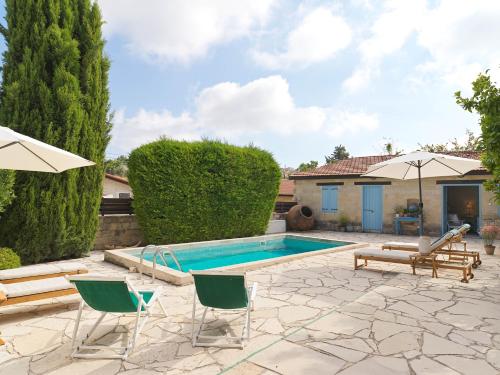 a swimming pool with chairs and umbrellas in a yard at Villa Avgoustis in Pachna