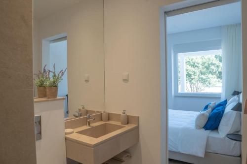 a bathroom with a sink and a bed with a mirror at NEW Estrela da Praceta Apt w/ 3 Suites & Oceanview in Carcavelos