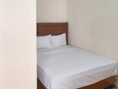 um quarto com uma cama com lençóis brancos em New Era Family Homestay Binjai Mitra RedDoorz em Binjai