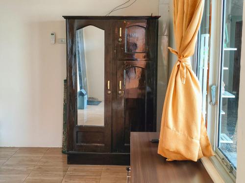 um armário de madeira com um espelho num quarto em New Era Family Homestay Binjai Mitra RedDoorz em Binjai