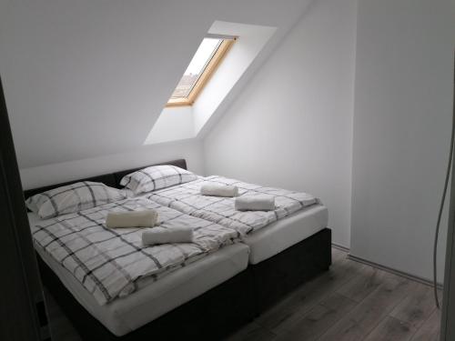 a bed in a white room with a window at Mohács Apartman in Mohács