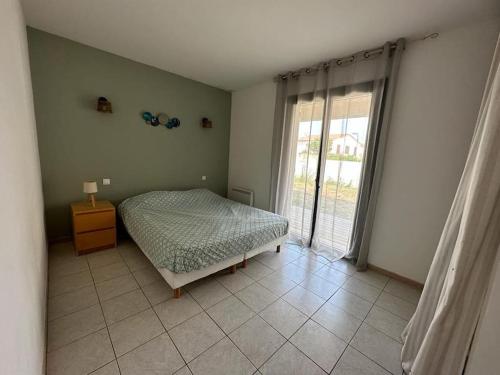 une chambre avec un lit et une grande fenêtre dans l'établissement Maison à deux pas des plages avec jardin, terrasses et spa., à Mèze