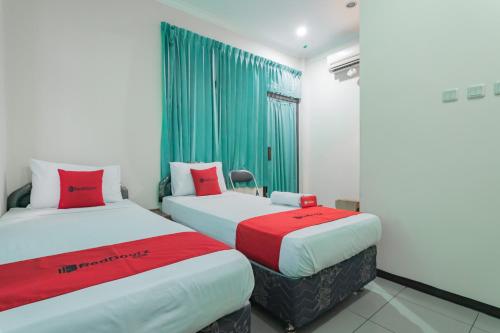 a room with two beds with red and white sheets at RedDoorz @ Achino Hotel Bandung in Bandung