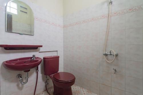 baño con aseo rojo y lavamanos en RedDoorz @ Achino Hotel Bandung, en Bandung