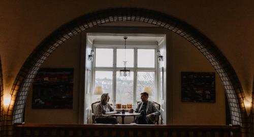a man and woman sitting at a table in front of a window at Hotel Slottsvillan in Huskvarna