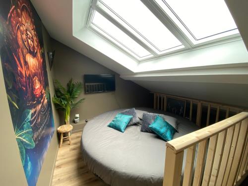 a bedroom with a bed with blue pillows and a skylight at A la Belle Étoile, le spa détente céleste in Loison-sous-Lens