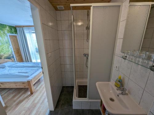 a bathroom with a shower and a sink and a bed at Haus Kathan in Kamering