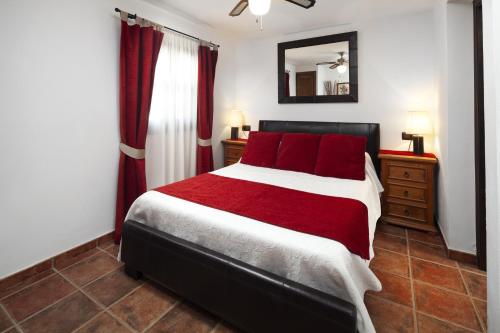 Schlafzimmer mit einem Bett mit roten Kissen und einem Spiegel in der Unterkunft Alter Real, luxury holiday retreat in Villanueva del Trabuco