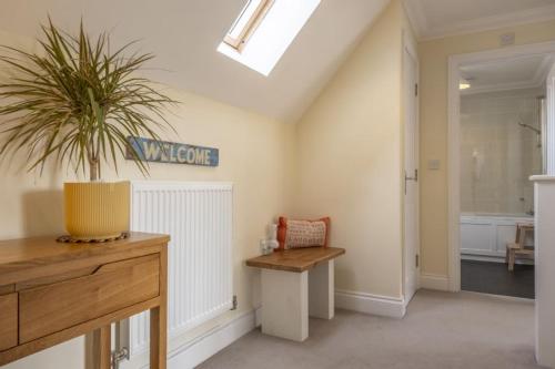 a bathroom with a bench and a plant in a room at The Coach House W in Wells next the Sea