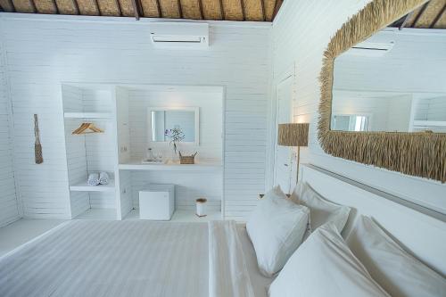 a white bedroom with a bed and a mirror at Stardust Villas in Nusa Lembongan