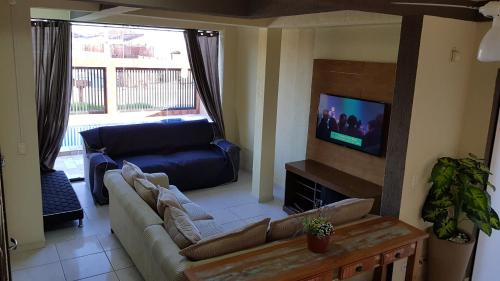 a living room with a couch and a flat screen tv at Triplex de veraneio em Guaratuba in Guaratuba