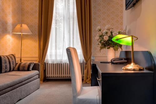 a living room with a desk with a lamp and a couch at Hotel Praga 1885 in Prague