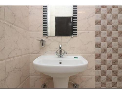 een badkamer met een witte wastafel en een spiegel bij Hotel Sparsh Ganga, Rishikesh in Rishīkesh