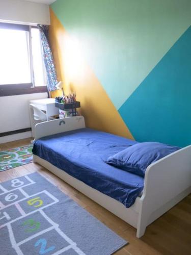- une chambre avec un lit et un mur coloré dans l'établissement Apartment Fontarabie CityCosy, à Paris
