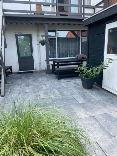 une terrasse avec un banc et des plantes devant une maison dans l'établissement Halte71, à Zandvoort