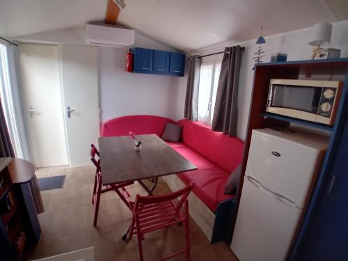 a living room with a red couch and a table at Mobil home 6 pers. climatisé in Agde