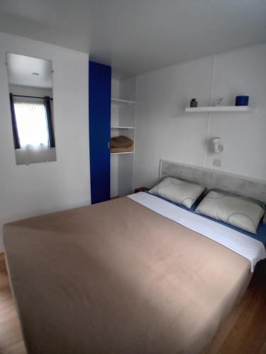 a bedroom with a large bed with a blue wall at Mobil home 6 pers. climatisé in Agde