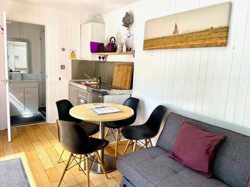 a living room with a couch and a table in a kitchen at Purple CargoPod at Lee Wick Farm Cottages & Glamping in Clacton-on-Sea