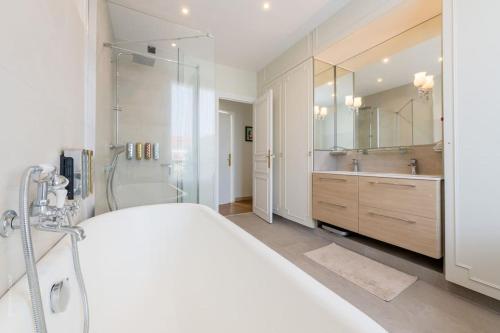 La salle de bains blanche est pourvue d'une douche et d'un grand lit. dans l'établissement Somptueuse maison- Piscine-Sauna-15 personnes - Calme, à Bois-Colombes