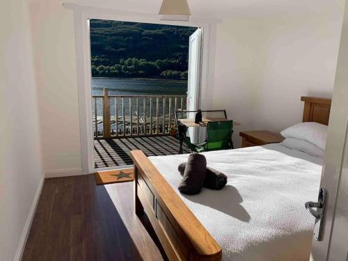 1 dormitorio con cama y ventana grande en Cottage on the Loch, en Arrochar