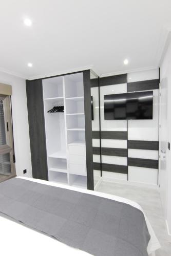 a bedroom with white walls and a bed with a tv at El Capricho de la ría II in O Grove