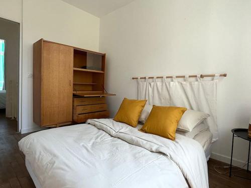 um quarto com uma cama branca e 2 almofadas amarelas em Loft avec jardin chez l'habitant em Bagnolet