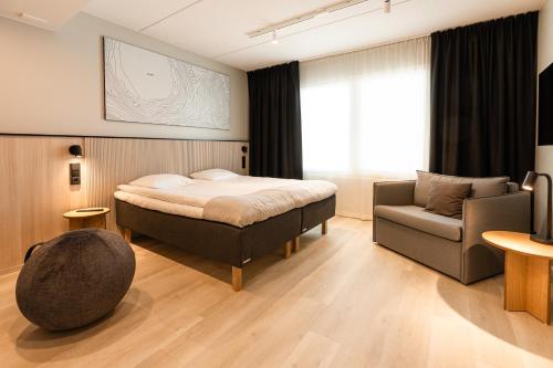 1 dormitorio con 1 cama, 1 silla y 1 sofá en Hotelli Fennada, en Vierumaki