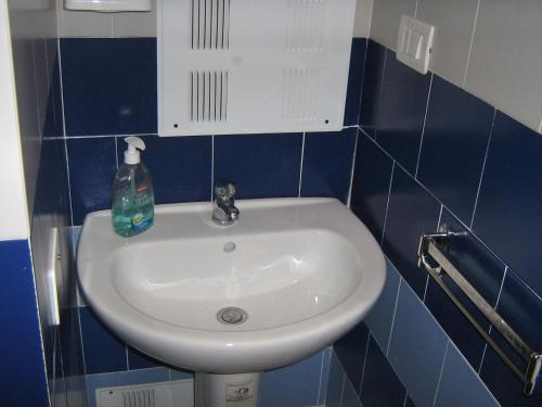 un lavabo blanco en un baño de azulejos azules en Flat in Milan 3, en Milán