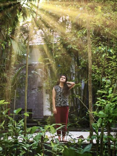 a woman standing in a forest of trees at Softouch Ayurveda Village Kerala in Kizhake Chālakudi